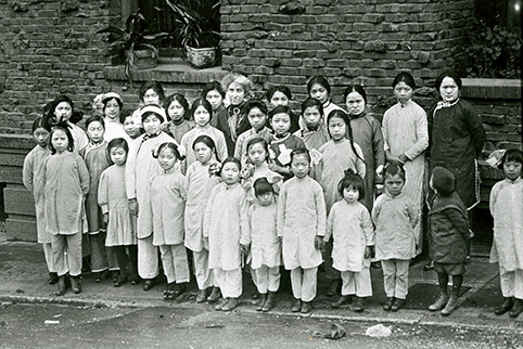 Tye Leung, second from left, back row, stands with a group of children and staff from the Presbyterian mission where she worked with Donaldina Cameron, center, a crusading anti-prostitution and anti-trafficking activist. Photo courtesy of the California History Room, California State Library, Sacramento, California.
