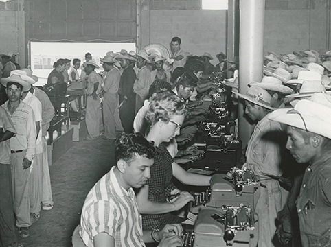 Room where people with type writers helped long lines of people wanting to come to the United States