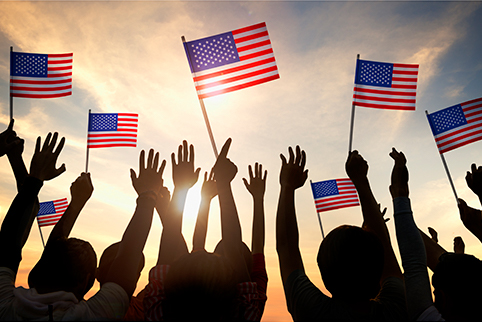 People with hands up waving American flags