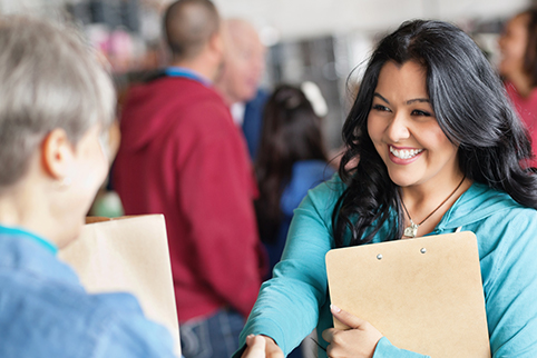 Woman talking to another person at an event where there are other people standing in the background