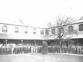 Picture of Old building with workers and people standing outside.